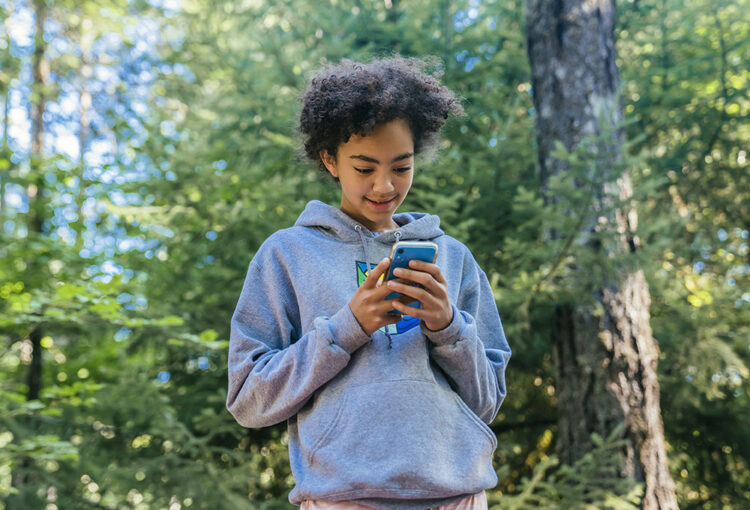 Teen looking at mobile phone in forest