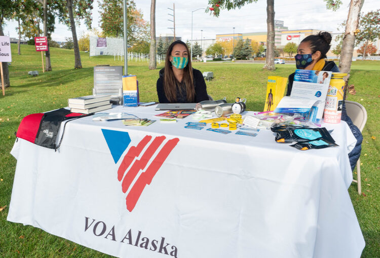 Two VOA Alaska staff at a table during an outdoor event