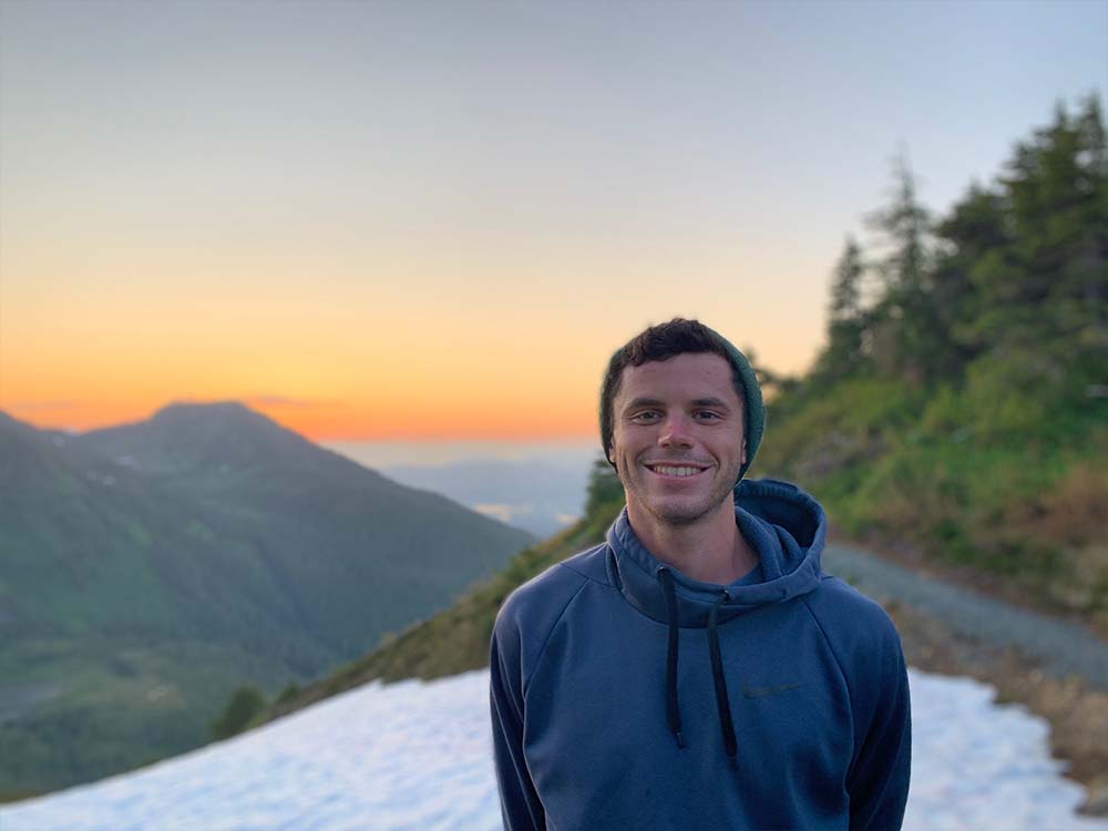 Young man standing on mountaintop at sunset