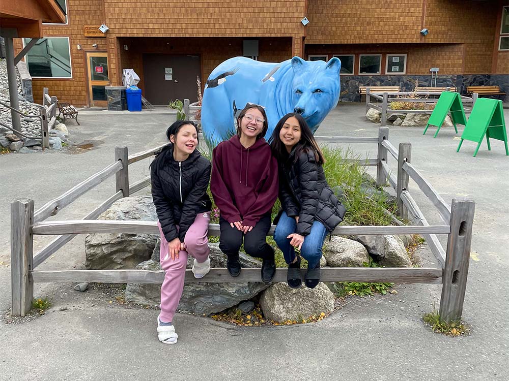 Three happy teens posing at entrance to zoo.