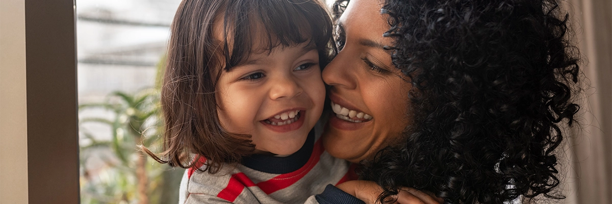 A caregiver holding a child close, both are smiling