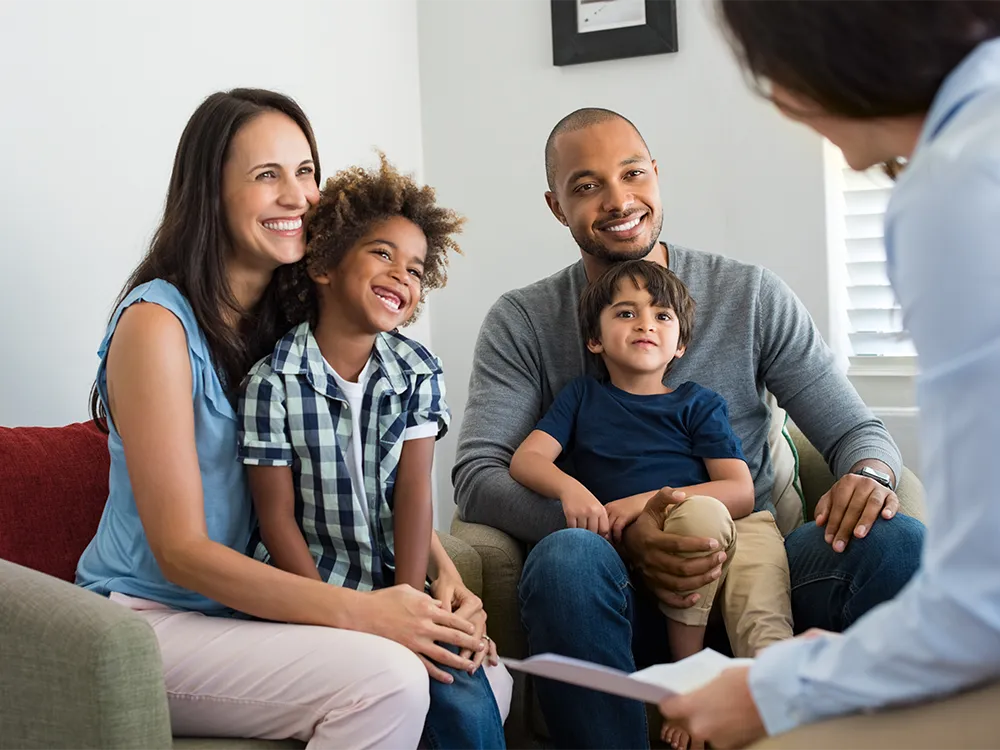 Two caregivers and two children smiling during a family therapy sessions