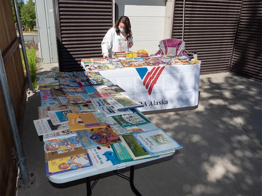 Person arranging books on a table for a book fair