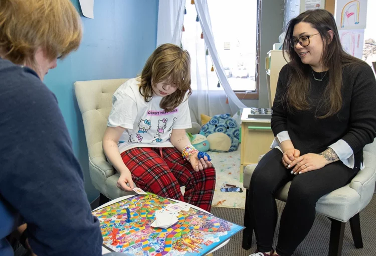 Clinician in family session playing Candy Land with a child and caregiver.