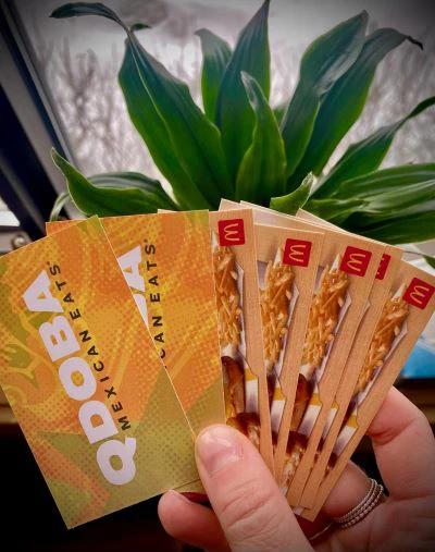 Qdoba and McDonalds gift cards fanned out in a person's hand