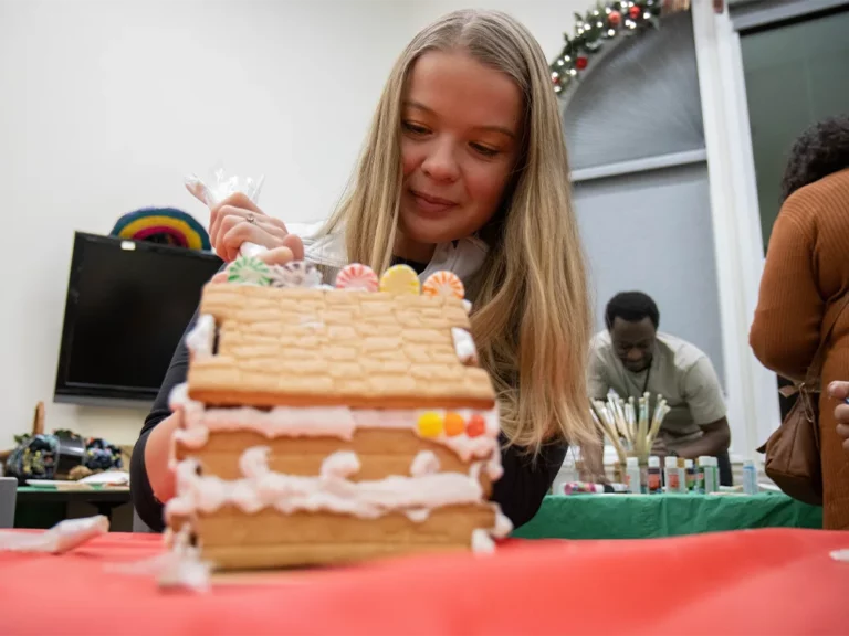 Low shot of a person decorating a gingerbread house