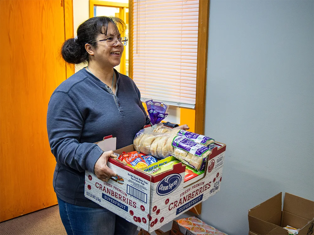 Person facing to the right side of the frame, holding a box of food donations.